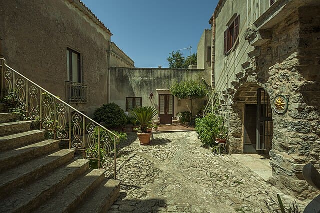 Vicolo di Erice con pavimentazione in balolato, archi in pietra e balconi fioriti