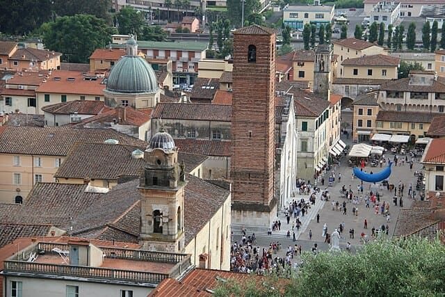 Pietrasanta: veduta aerea tra i tetti del borgo, il Duomo e la costa della Versilia all'orizzonte.