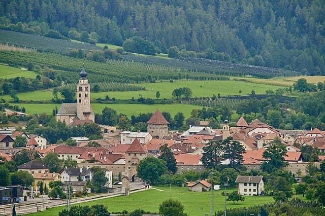 Glorenza in Val Venosta: la città medievale con mura intatte e torri storiche, sovrastata dall'Ortles innevato.