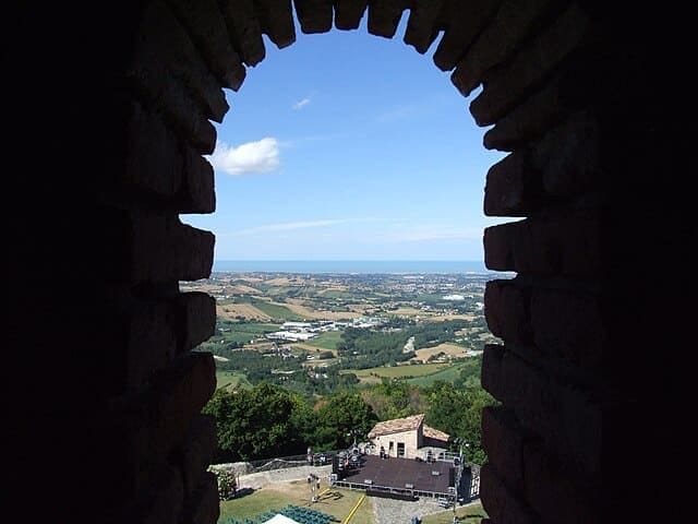 Veduta aerea della maestosa Rocca Malatestiana di Montefiore Conca che domina la valle al tramonto.