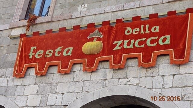 Rievocazione medievale durante la Festa della Zucca a Venzone con figuranti in abiti storici e decorazioni di zucche.