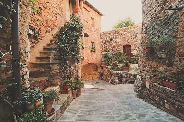 Campiglia Marittima: scorcio di un vicolo medievale con archi in pietra e vasi di fiori colorati.