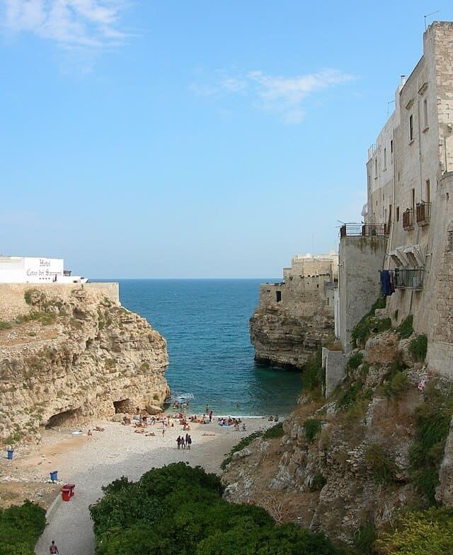 Polignano a Mare: le case bianche a picco sul blu Adriatico e la celebre cala Lama Monachile tra le rocce della costa.