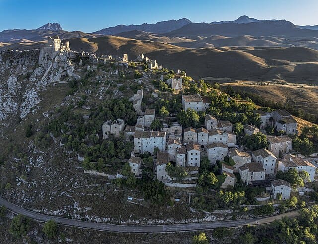 Rocca Calascio: panorama mozzafiato del borgo medievale con le maestose vette del Gran Sasso sullo sfondo.