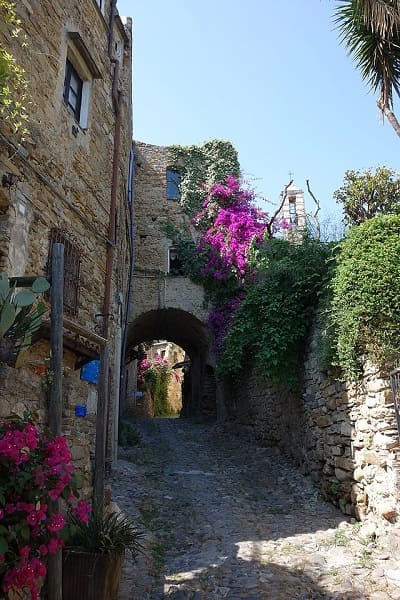 Antichi vicoli in pietra del borgo di Bussana Vecchia con laboratori artigiani e archi medievali.