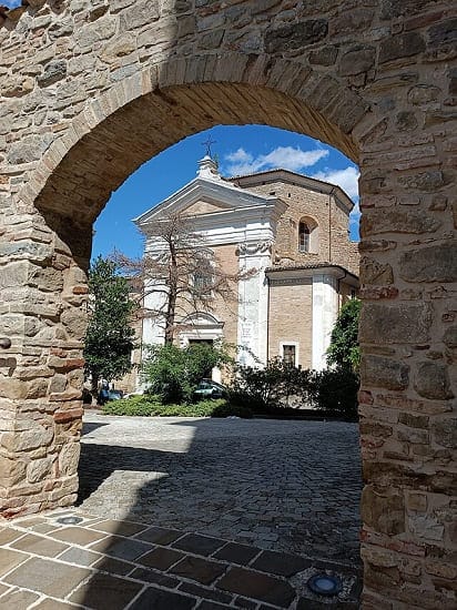 Scorcio di un vicolo medievale nel centro storico di Cingoli con case in pietra e vasi di fiori.