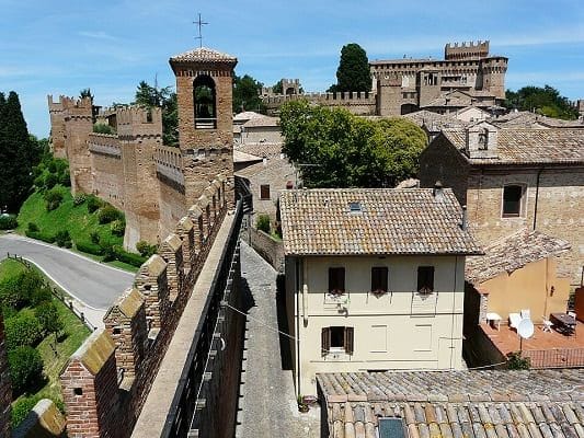 Veduta aerea panoramica della Rocca di Gradara e del suo borgo fortificato, situati sulle colline marchigiane con vista verso l'orizzonte adriatico.