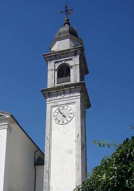 Veduta del borgo di Pesariis con orologio monumentale ad acqua e case tipiche in pietra carnica
