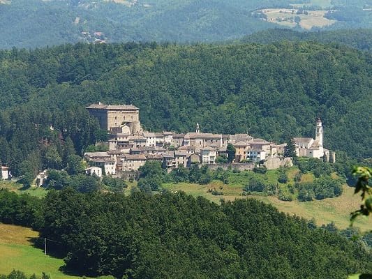 Panorama del borgo medievale di Compiano arroccato sulla collina con il castello Landi e i boschi della Val Taro.
