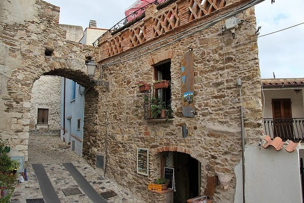 Scorcio del centro storico medievale di Posada in Sardegna, con un vicolo in pietra e tipiche case colorate senza persone.